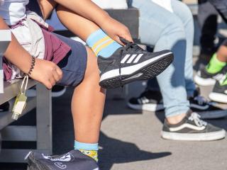 Students try on shoes on the playground during the Shoes That Fit event. 