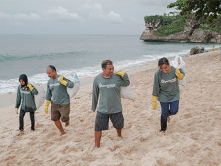Four volunteers picking up trash on a beach