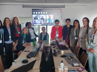 A small team in a conference room, a screen up with virtual participants.