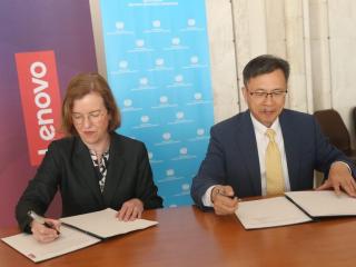 Two people seated at desk, signing letters