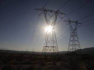Tall power lines lined up with the sun over a large flat open landscape