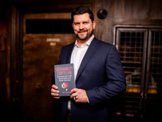 Mike Hower holding his new book