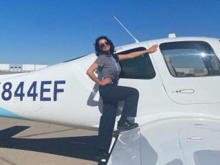 Natalie Villalpando, in sunglasses, stands on the wing of a small plane