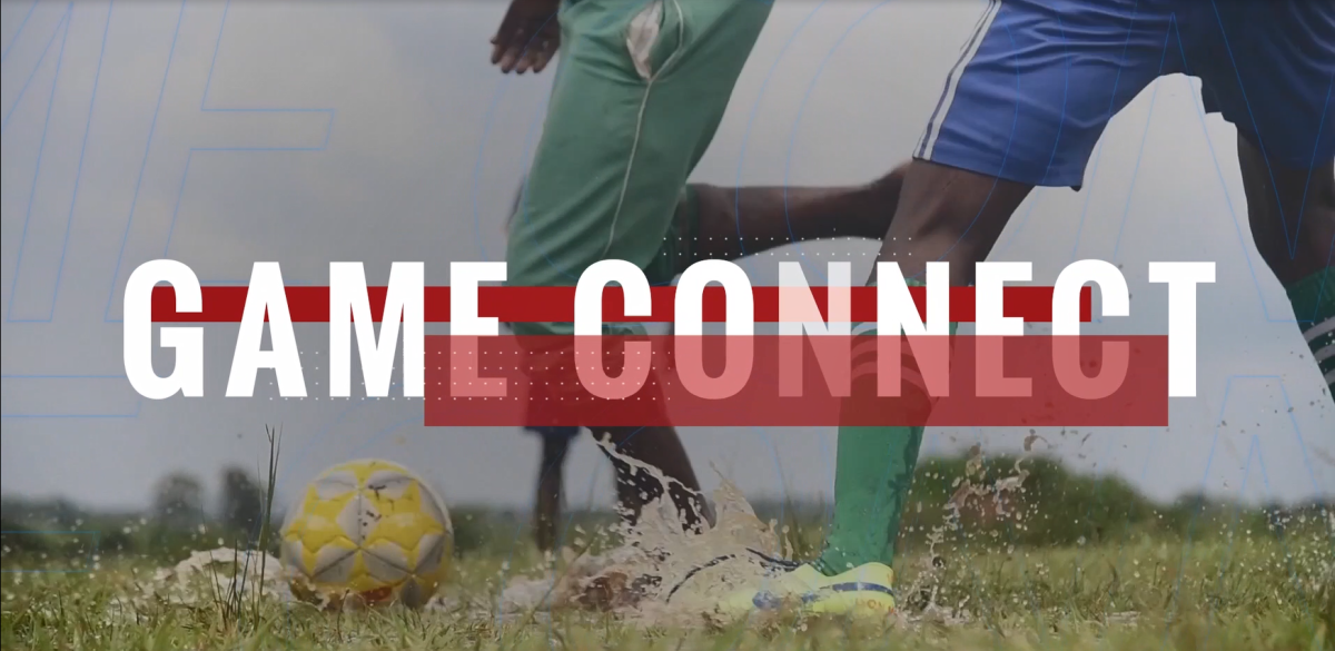 Two soccer players' legs and a soccer ball. Water splashes from the field.