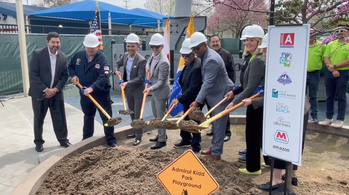 A group of people with hard hats and gold shovels in a ground breaking ceremony.