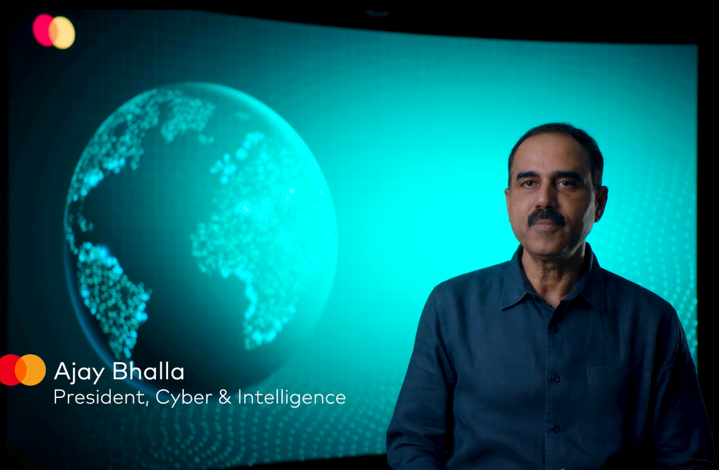 Ajay Bhalia in front of a digital screen of a globe.