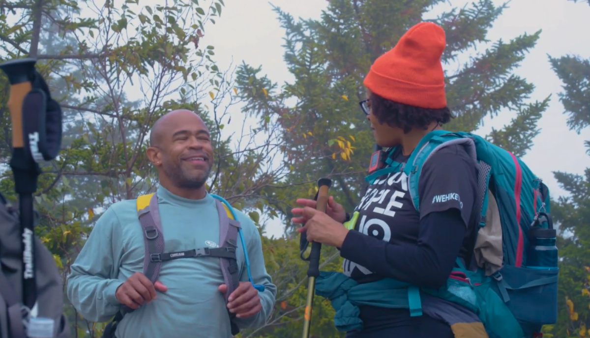 two hikers talking in front of trees