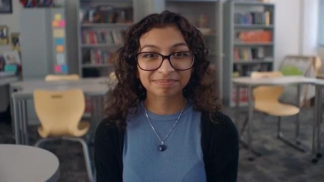 Person wearing glasses and a blue top , smiling into the camera