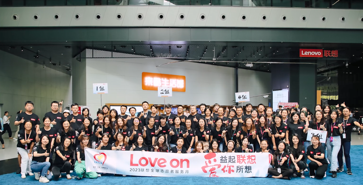Large group posed, holding a large banner "Love On" and other writing in a foreign language.