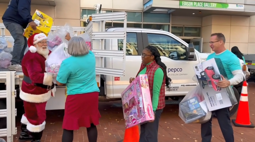 Volunteers lined up to help Santa load presents on the back of a Pepco truck.