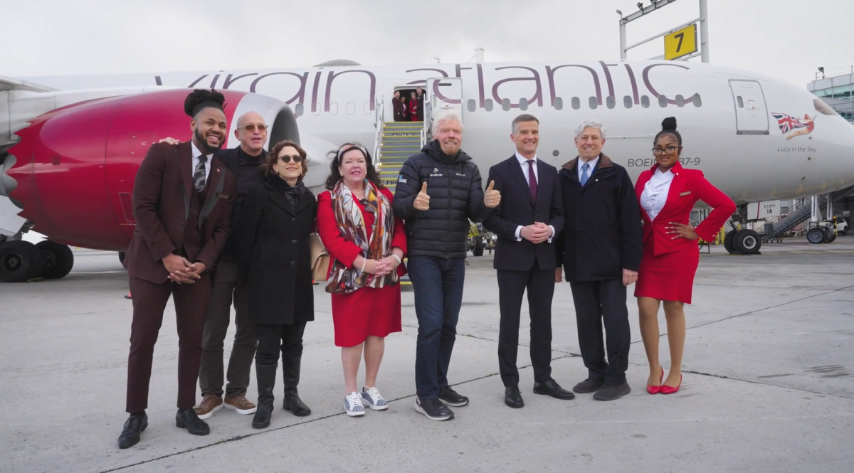 A group of people pose in front of a Virgin Atlantic plane.
