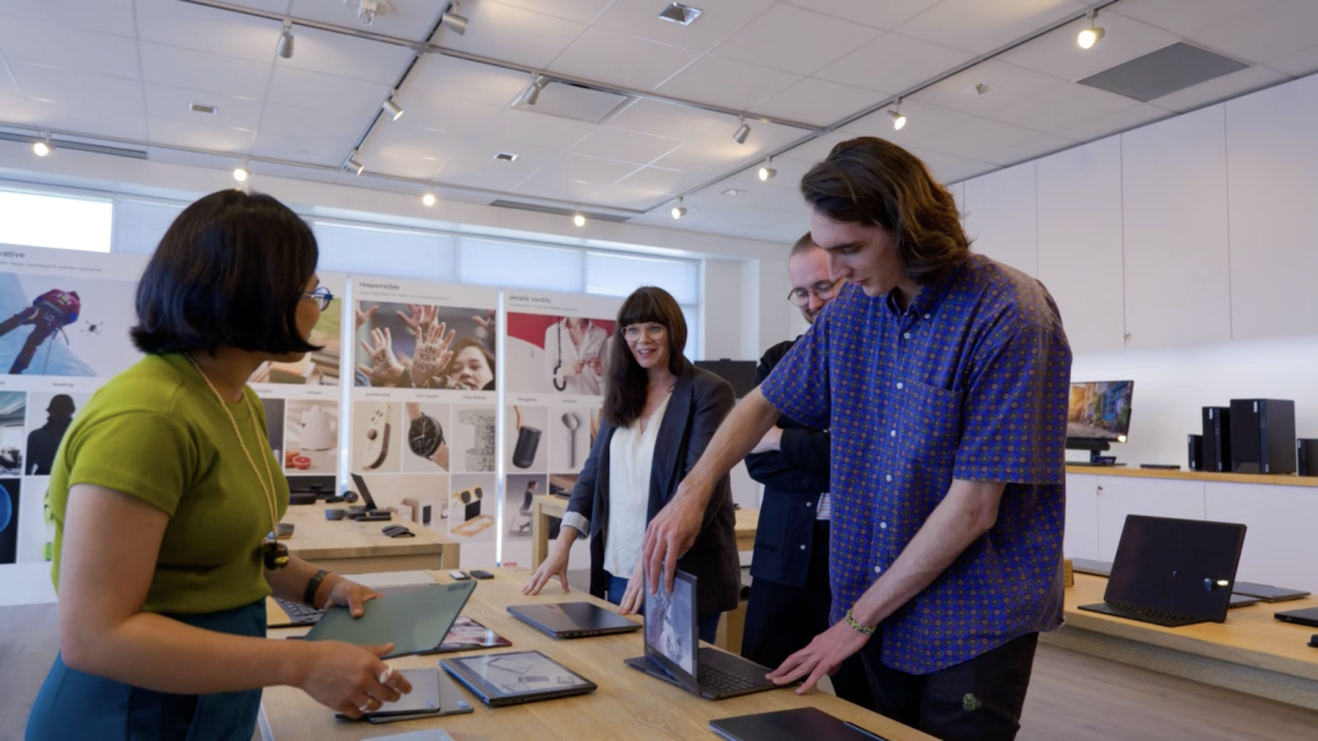 People stood around a desk which has laptops on