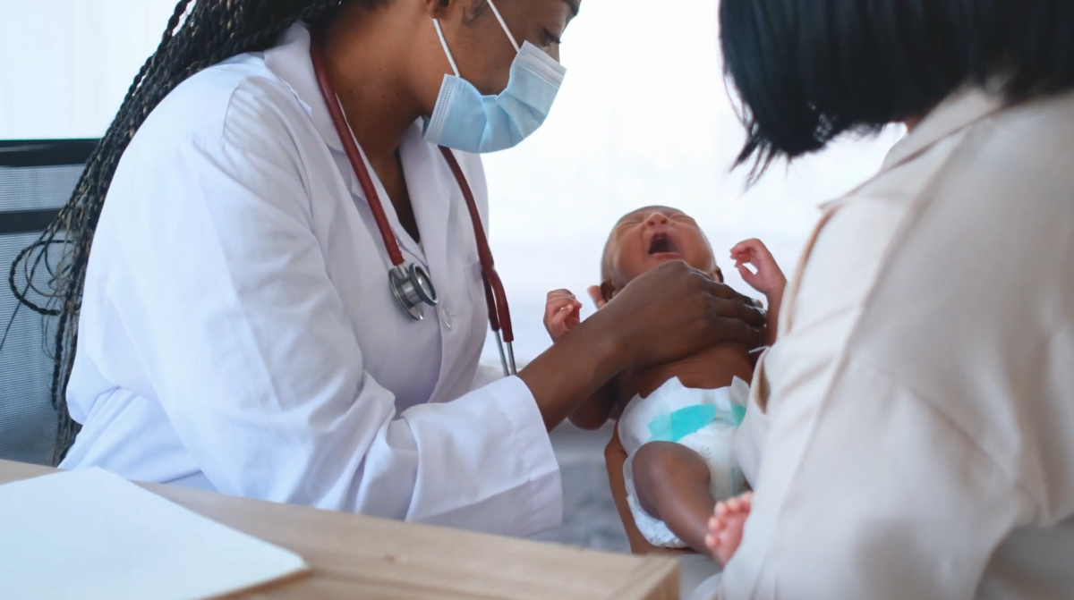 A medical provider and another adult holding an infant in a diaper.