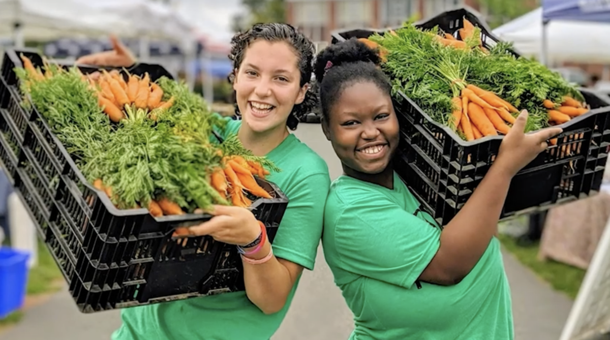 2 people holding baskets of carrots