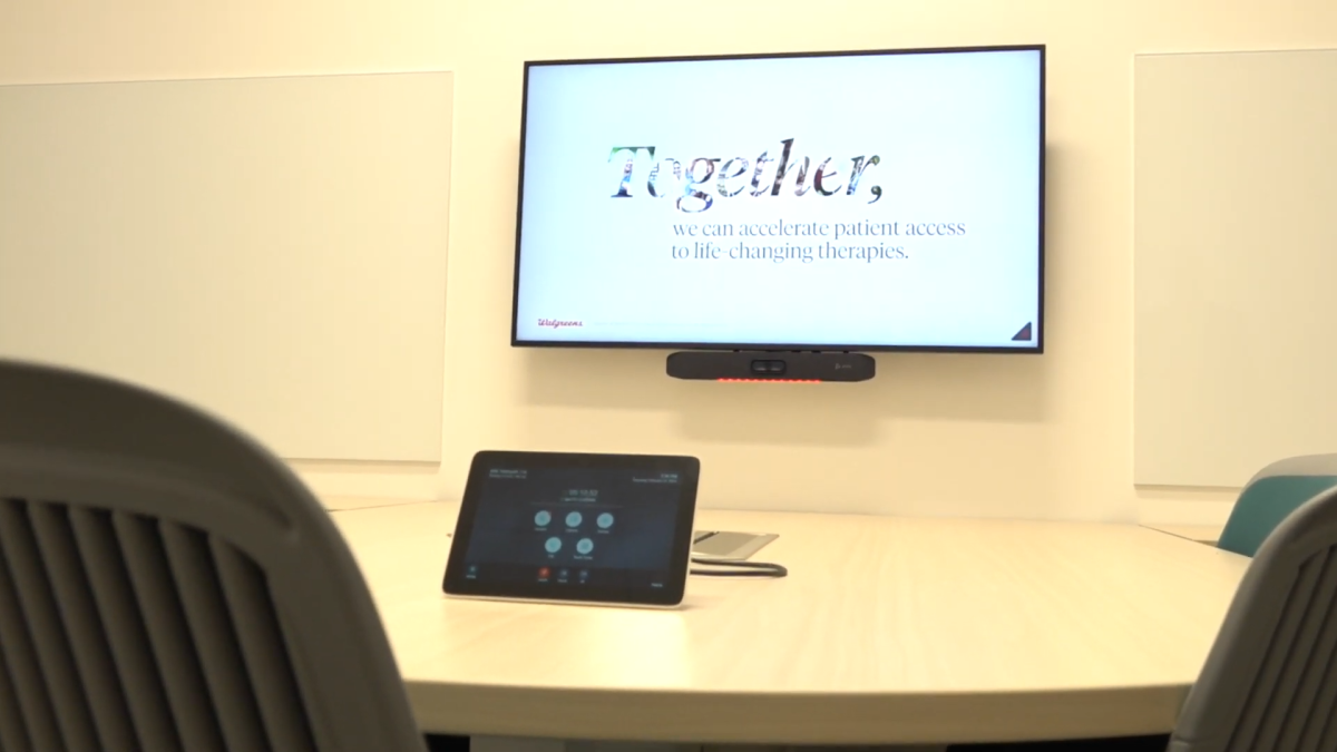 A screen on the wall that reads "Together, we can accelerate patient access to life-changing therapies"