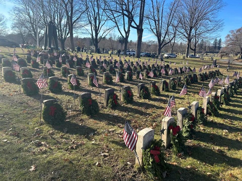 Wreaths placed on headstones with American flags