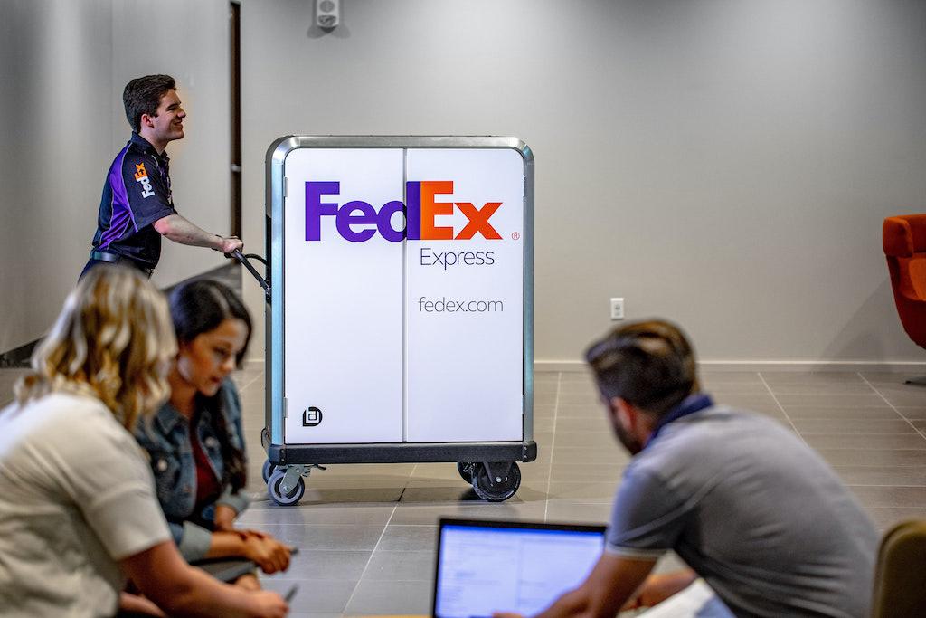 Person in a FedEx uniform pushing an electric pallet