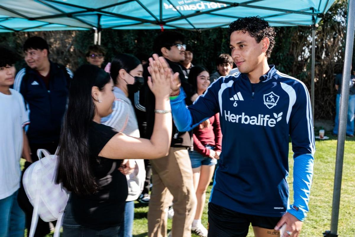 LA Galaxy player Edwin Cerillo greets a student during a meet‑and‑greet at a preseason training session, creating personal connections through sport and mentorship.