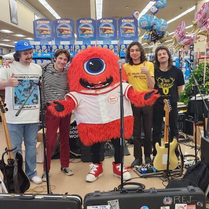 Band posing with Jewel-Osco mascot, JoJo, at store event