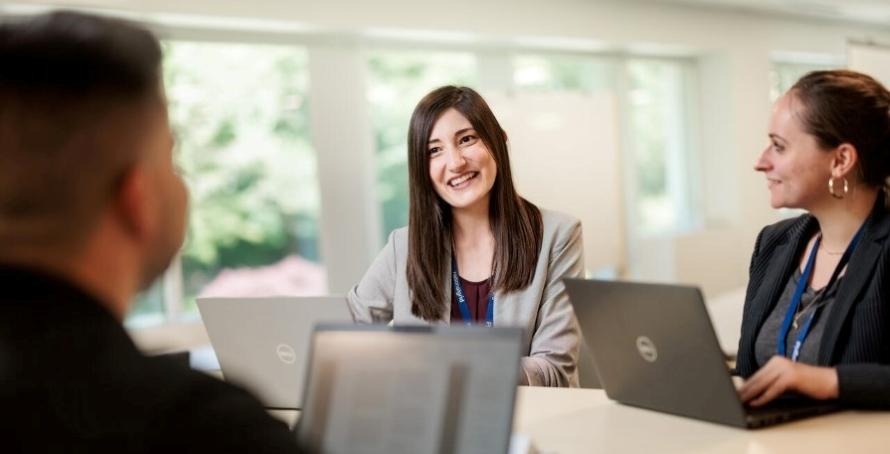 Group photo of employees working from laptops looking happy 