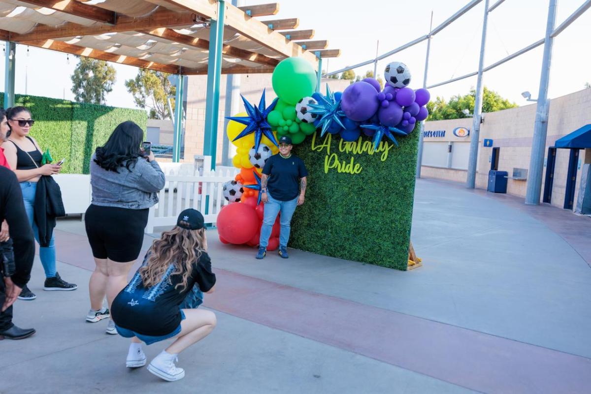 LA Galaxy fans taking photos at an LA Galaxy Pride Night photo station.