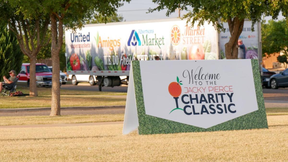 Sign with text "Welcome to the Jacky Pierce Charity Classic" in front of an Albertsons Market trailer