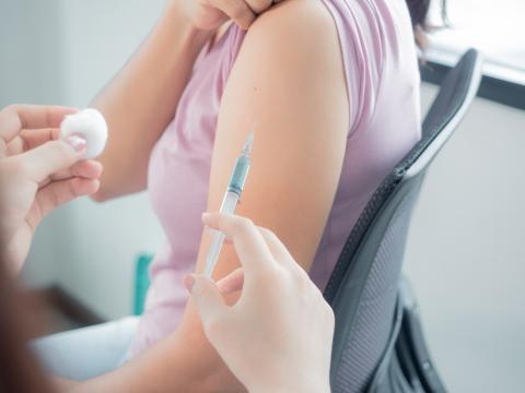 Pharmacist preparing to provide treatment to patient with an injection needle and cotton ball.