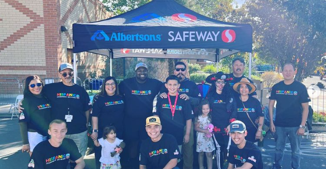 Group of people pose in front of Albertsons' tent for picture at Annual Chile & Frijoles Festival