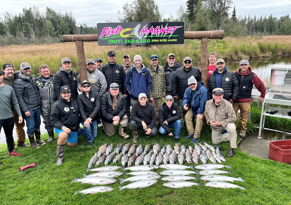 Group posing behind caught fish on the grass