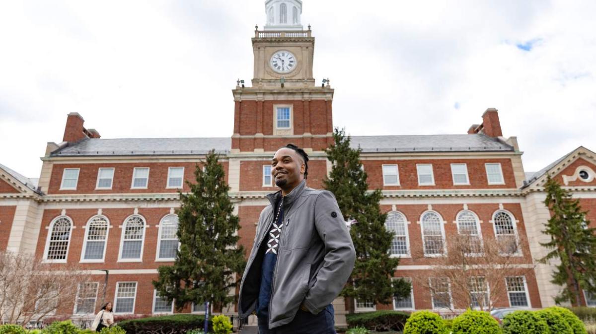 Dr. Kofi LeNiles stands in front of a building