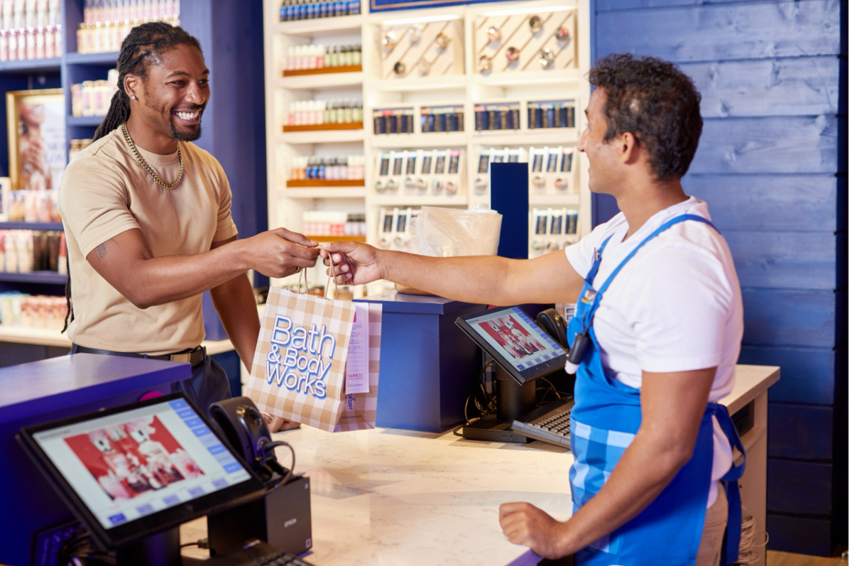 A Bath & Body Works employee handing a bag across the counter to a customer