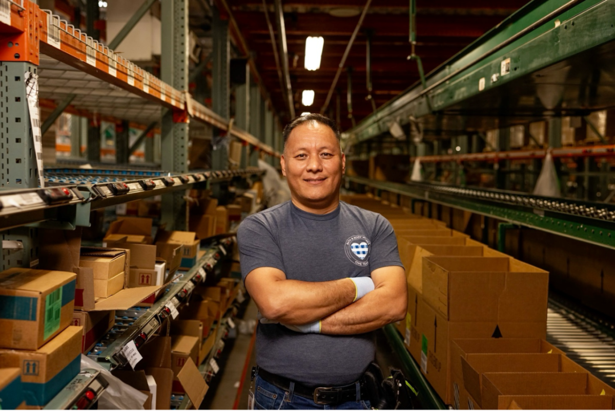 A person standing in a warehouse surrounded by shelves and boxes
