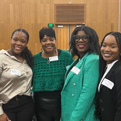 Four people stand together smiling