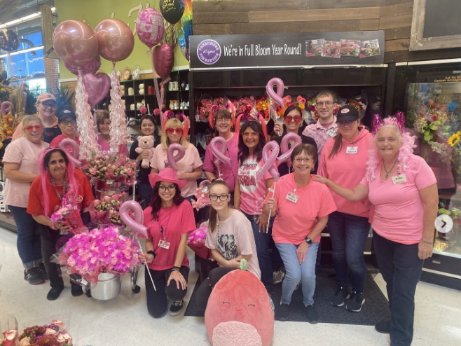 Group of people in pink shirts posing in a Jewel-Osco store