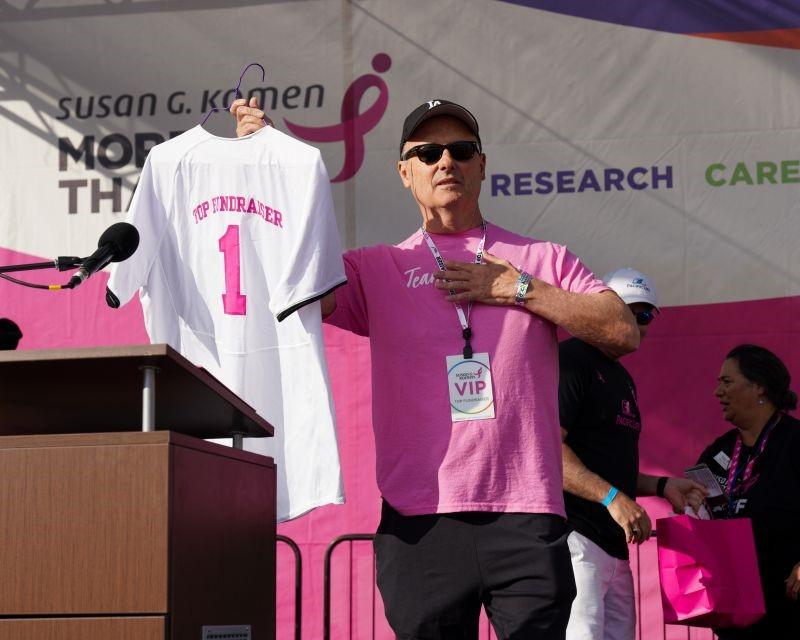 Man holding t-shirt jersey with #1 and Top Fundraiser on back.