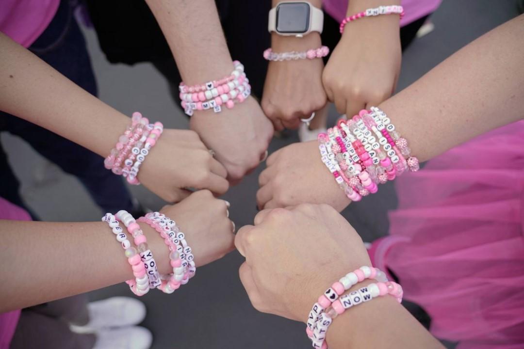 Picture of arms with pink friendship bracelets.