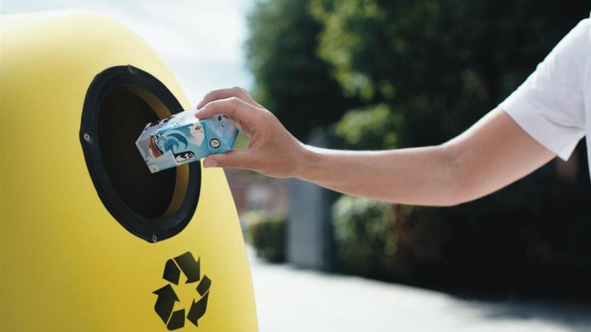 a carton being thrown into a yellow recycling bin