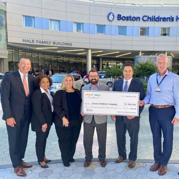Group of people holding large check in front of Boston Children's Hospital