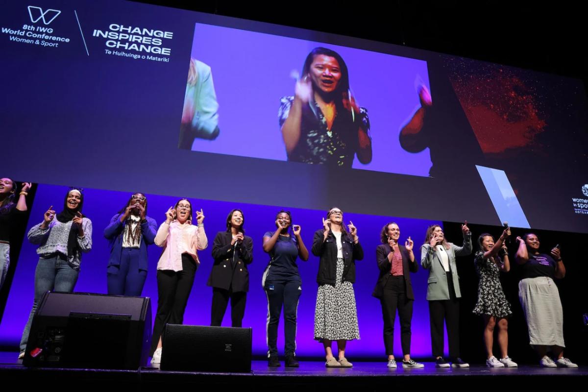 11 people standing in a row on stage.