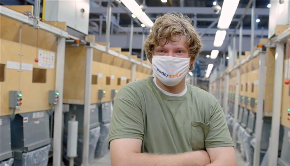 Image of a man in a green t-shirt wearing a mask over his nose and mouth