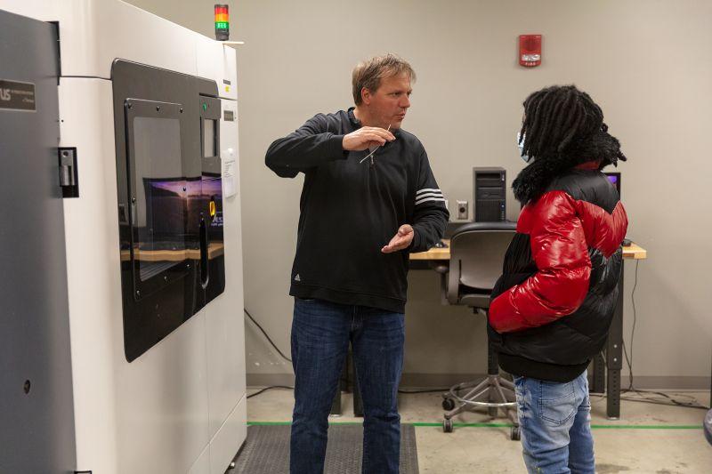 Whirlpool mentor talks with Benton Harbor High School student in front of a wall-mounted appliance