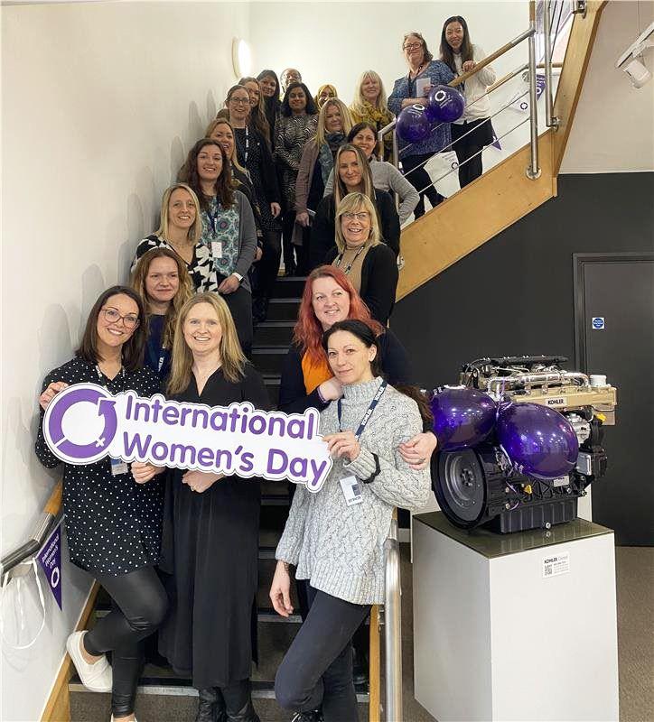 Women on staircase holding International Women's Day sign