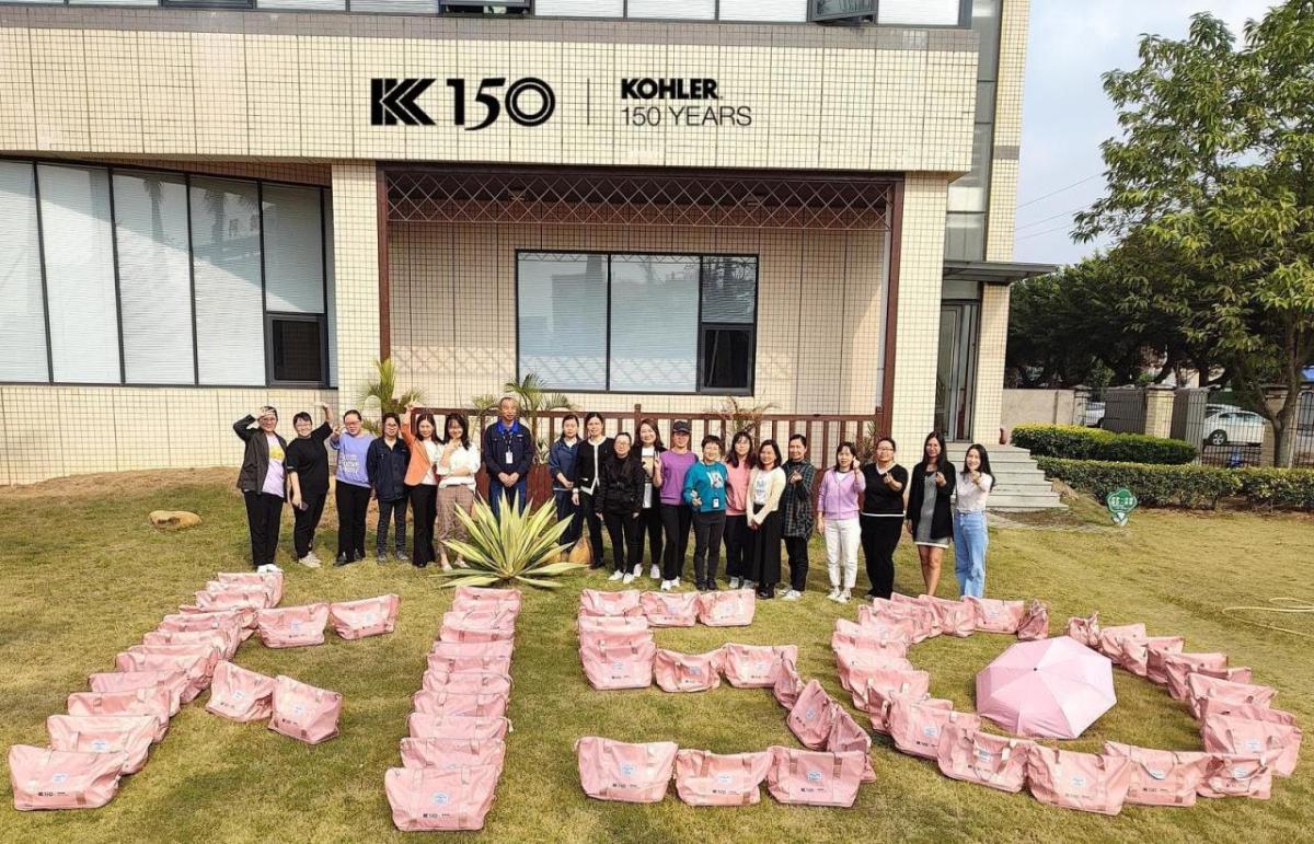 Group of people standing behind bags arranged to spell out K 150