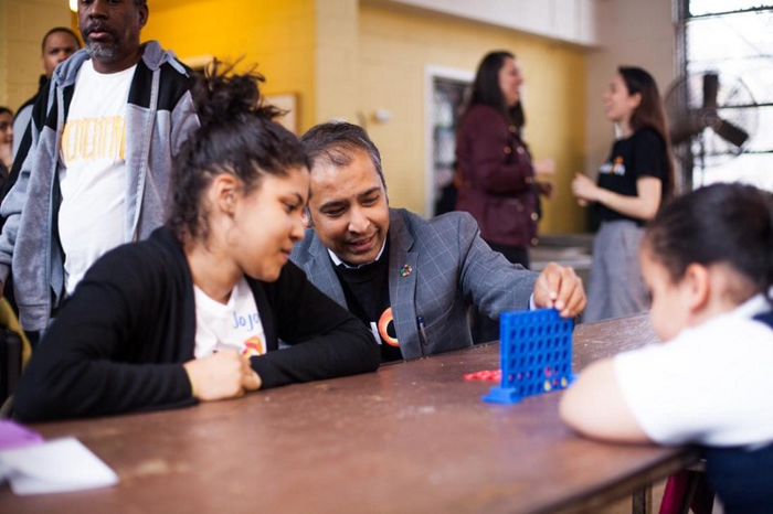 Balaji Ganapathy plays connect four with two students 