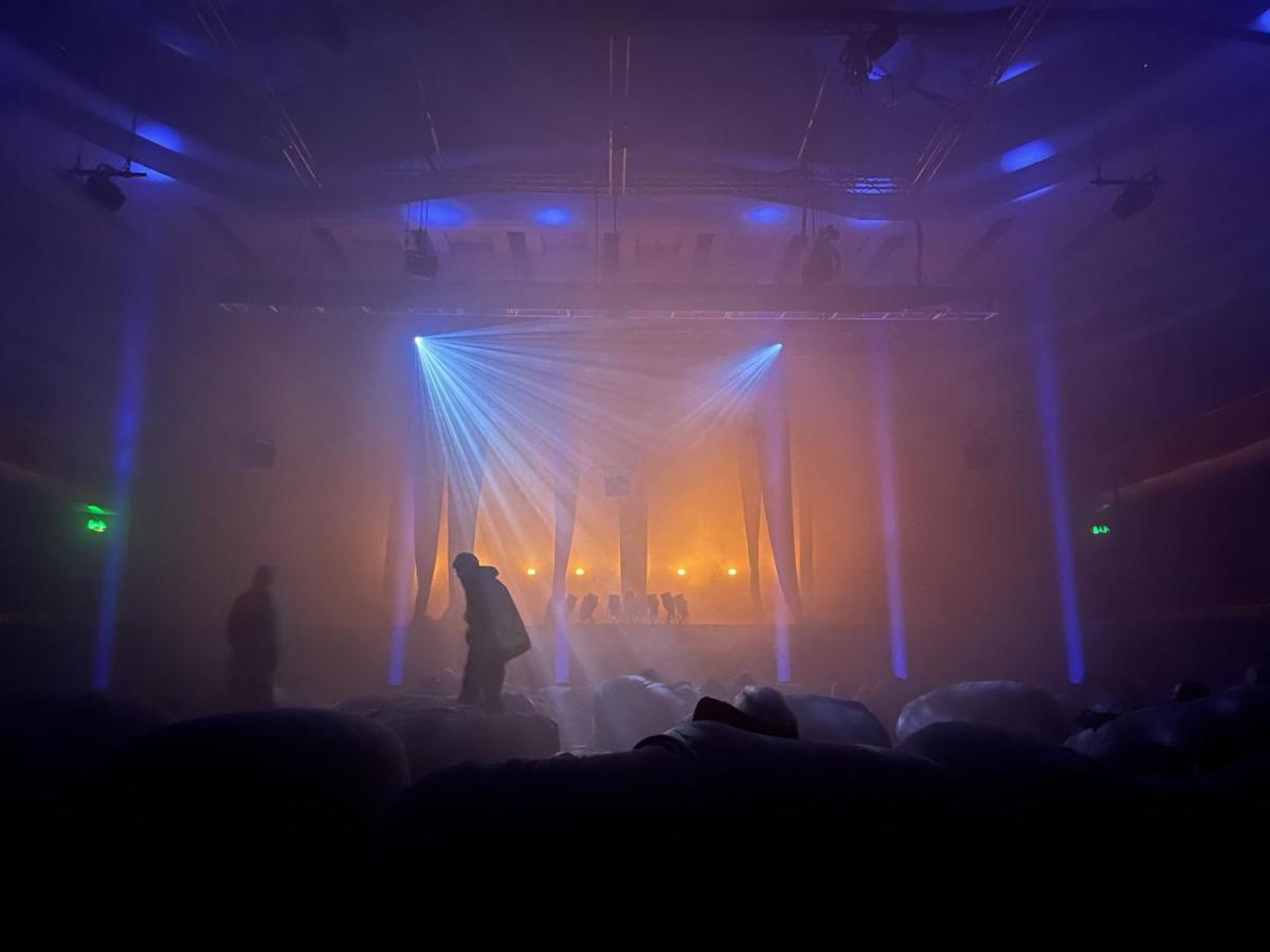 dark image with colored lights and people with bean bags