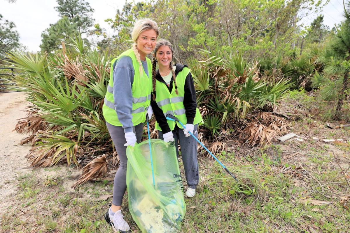Two friends smile as they volunteer to their time to clean up the Fort Morgan area.