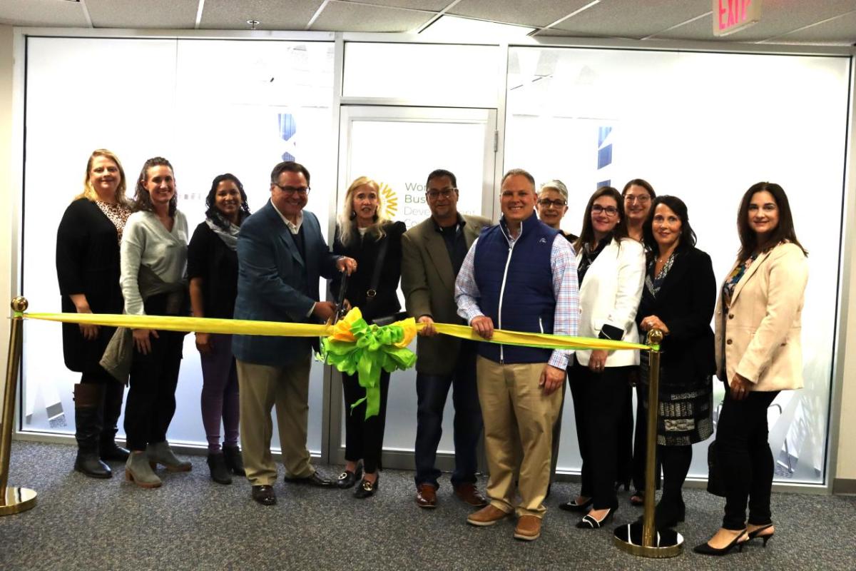 People standing together behind a ribbon about to be cut