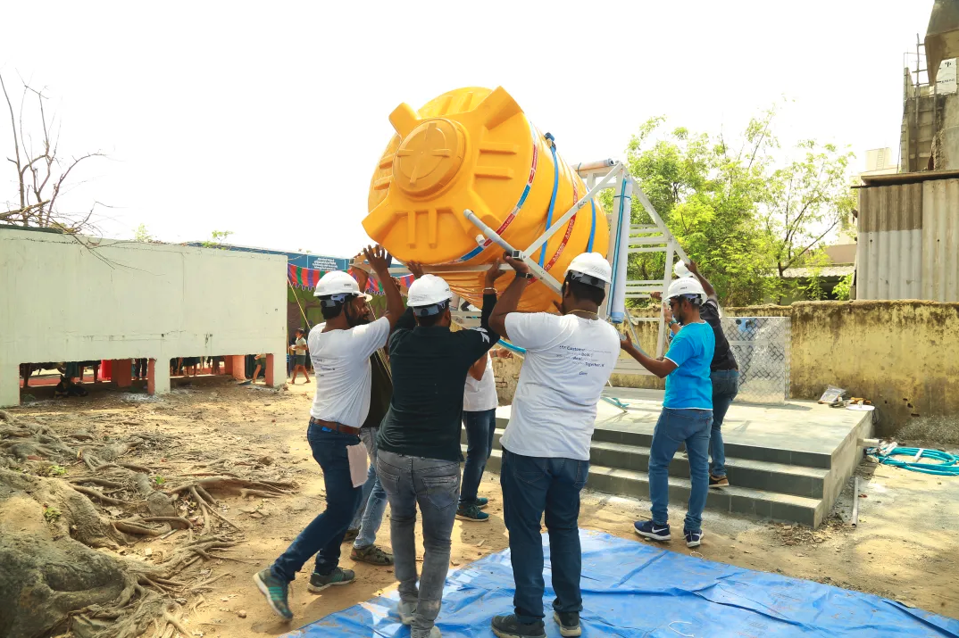 People lifting a large water container onto a platform