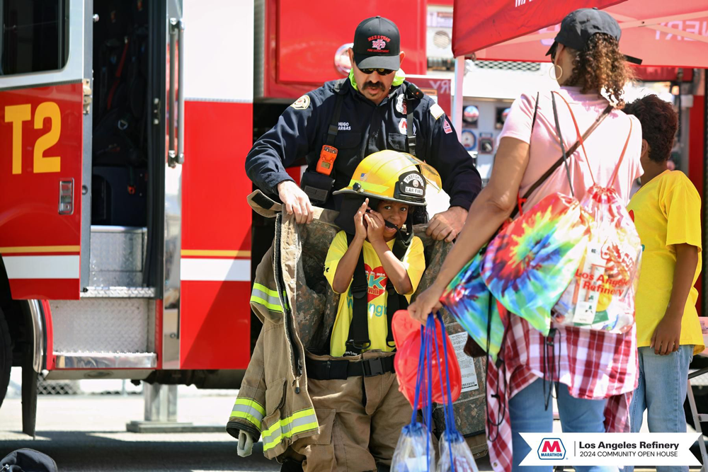 A child getting help putting on adult firefighting gear