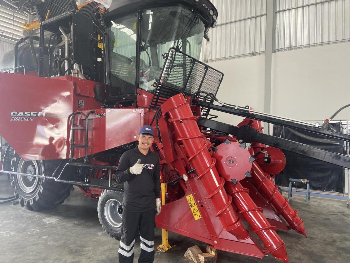 A person stood next to agricultural machinery 